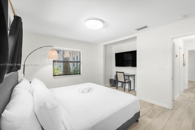 bedroom featuring light wood finished floors, visible vents, and baseboards