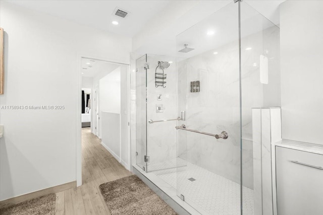 full bath featuring a marble finish shower, visible vents, baseboards, recessed lighting, and wood finished floors