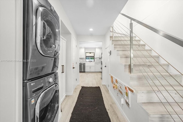 laundry room featuring stacked washer and clothes dryer, laundry area, and light wood finished floors