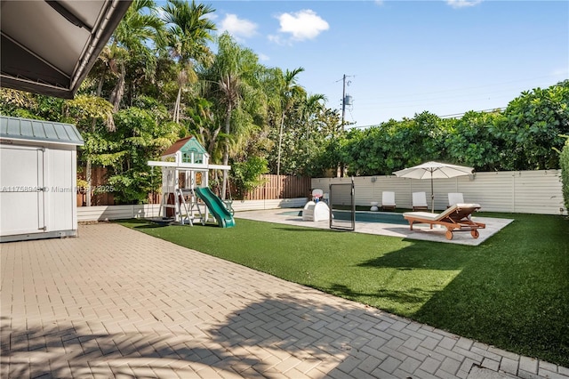 view of yard with a storage unit, a patio, a fenced backyard, an outdoor structure, and a fenced in pool