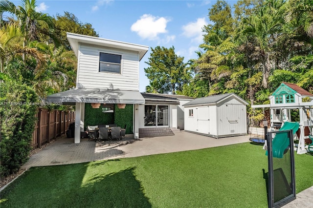 back of house with a storage shed, a patio, a yard, and an outbuilding