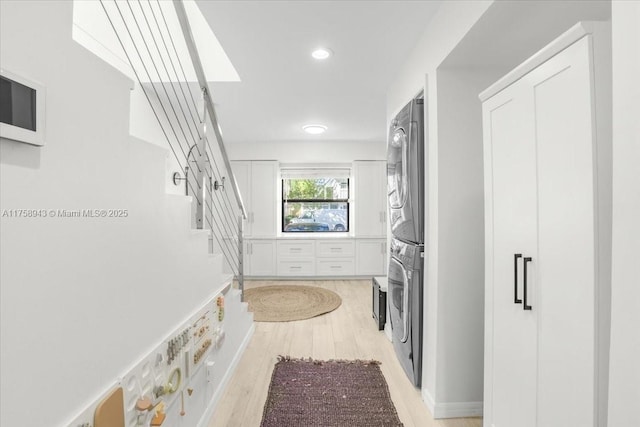 corridor with recessed lighting, light wood-style floors, stairs, and stacked washing maching and dryer