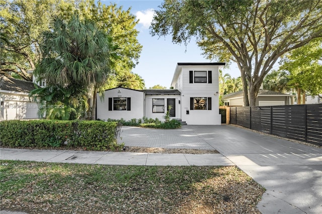 view of front of house with concrete driveway, fence, and stucco siding