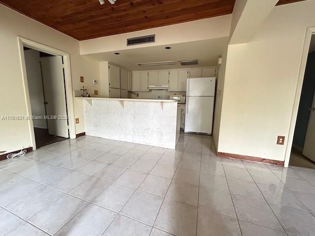 kitchen with visible vents, under cabinet range hood, freestanding refrigerator, a peninsula, and wooden ceiling