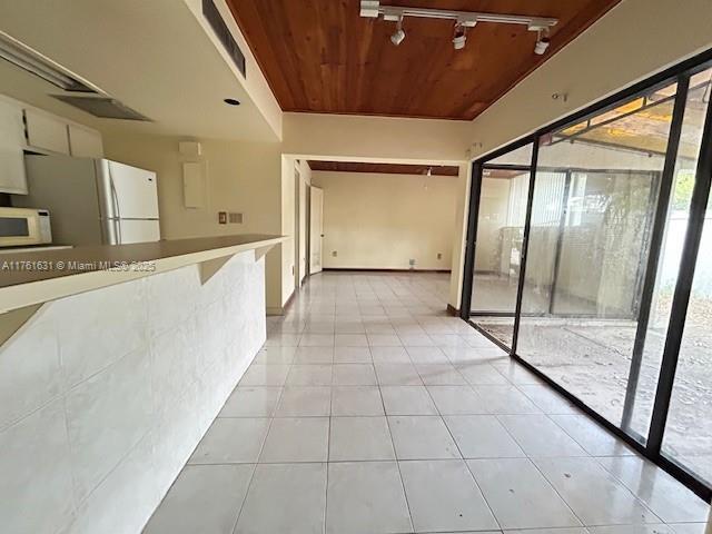 interior space with light tile patterned floors, wooden ceiling, and rail lighting