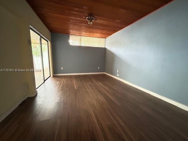 unfurnished room with dark wood finished floors, wooden ceiling, and baseboards