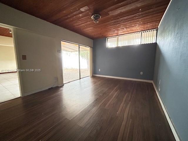 spare room featuring wood finished floors, wood ceiling, and baseboards