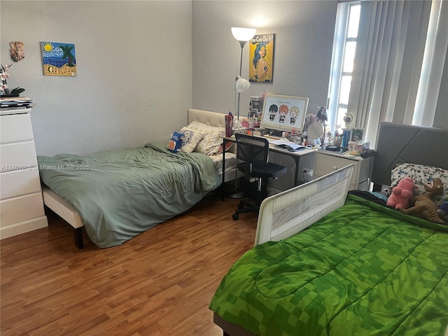 bedroom with wood finished floors and a textured wall