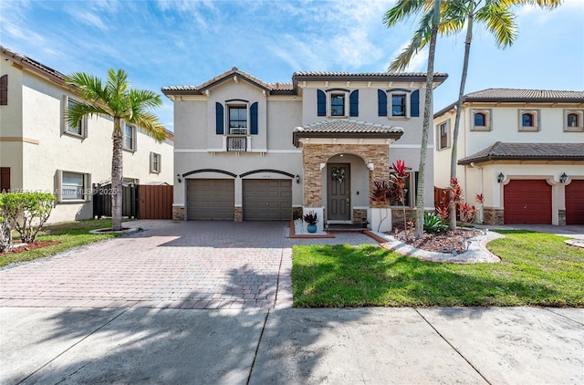 mediterranean / spanish-style home featuring decorative driveway, stone siding, an attached garage, and stucco siding