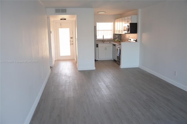 kitchen featuring visible vents, backsplash, appliances with stainless steel finishes, wood finished floors, and white cabinetry