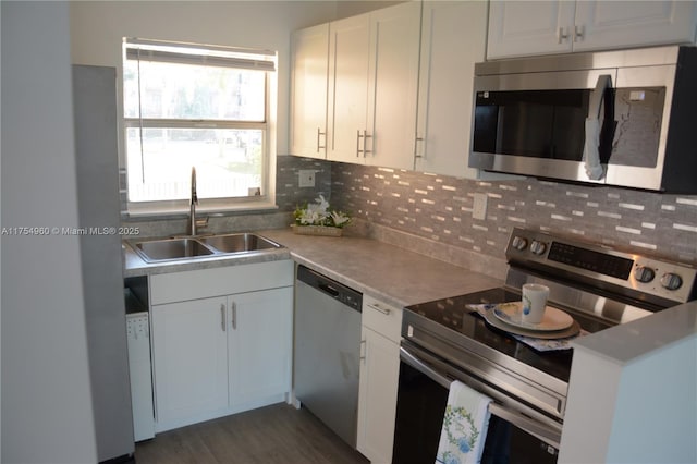 kitchen with dark wood finished floors, a sink, white cabinets, appliances with stainless steel finishes, and tasteful backsplash