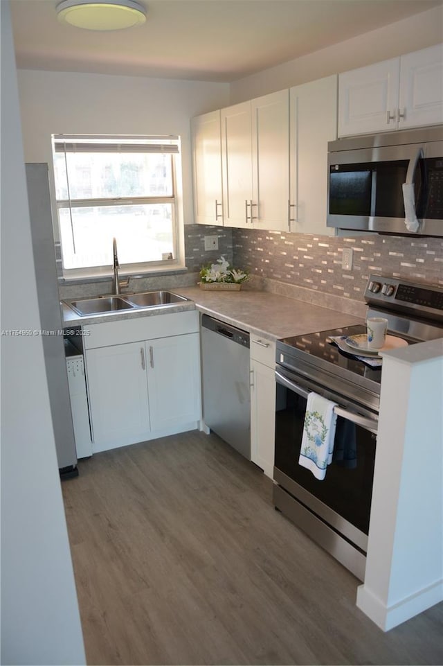 kitchen featuring a sink, stainless steel appliances, backsplash, and white cabinetry