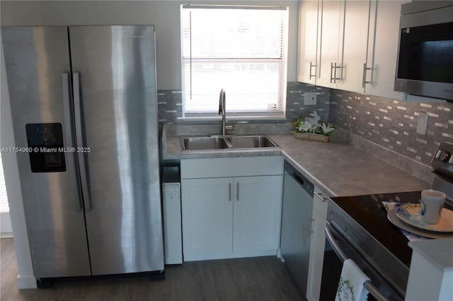 kitchen featuring tasteful backsplash, dark wood-style floors, white cabinets, stainless steel appliances, and a sink