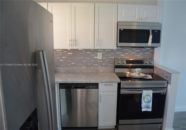 kitchen featuring stainless steel appliances, tasteful backsplash, light countertops, and white cabinetry