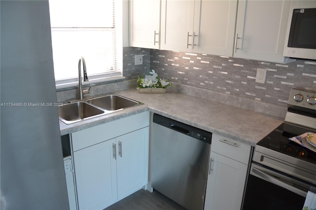 kitchen featuring a sink, backsplash, white cabinetry, stainless steel appliances, and light countertops