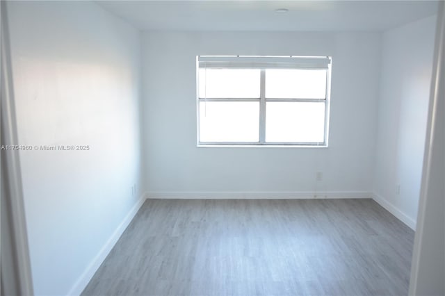 spare room featuring baseboards and light wood-type flooring