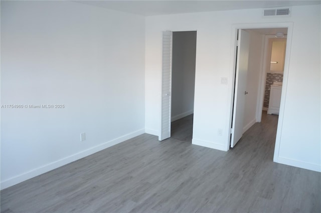 unfurnished bedroom with visible vents, baseboards, and wood finished floors