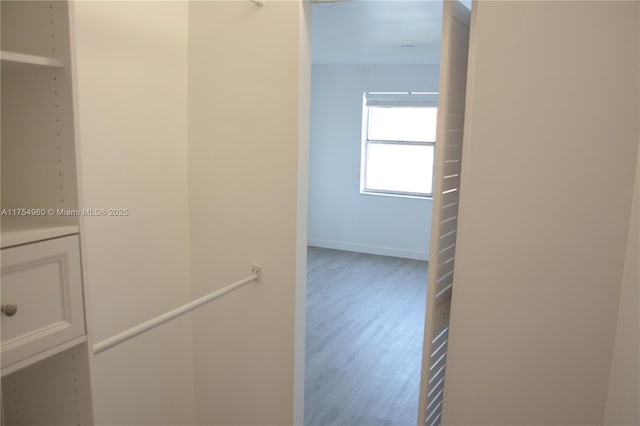 hallway with baseboards, an upstairs landing, and wood finished floors