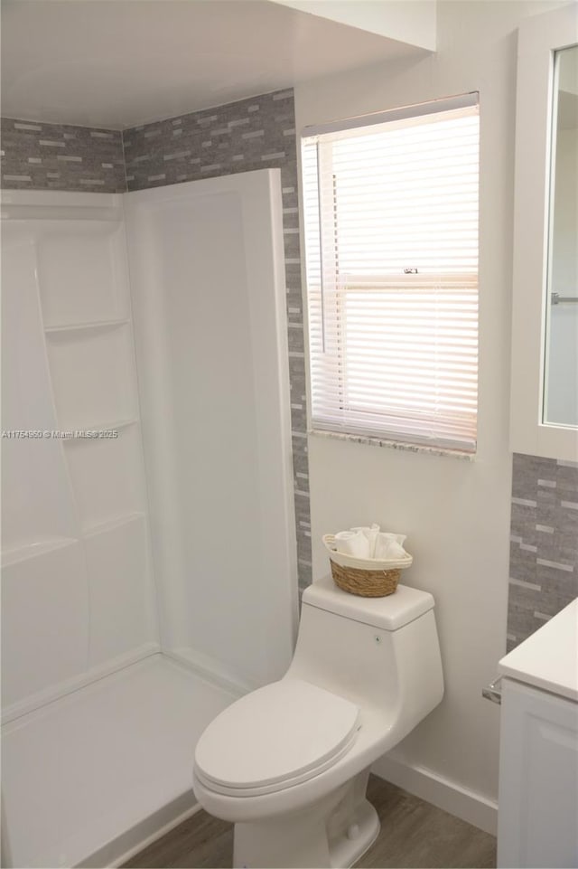 bathroom featuring vanity, toilet, wood finished floors, and walk in shower