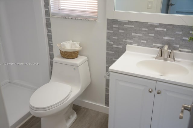 bathroom featuring vanity, toilet, wood finished floors, and tasteful backsplash