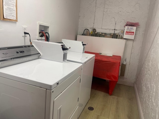 laundry room with separate washer and dryer, light wood-style floors, and baseboards