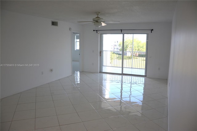 spare room featuring light tile patterned floors, visible vents, a textured ceiling, and ceiling fan