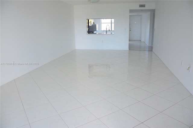 spare room featuring light tile patterned flooring, visible vents, and a sink