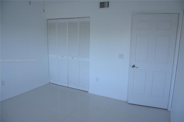 unfurnished bedroom featuring visible vents, a closet, and tile patterned flooring