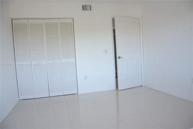 unfurnished bedroom featuring tile patterned floors, visible vents, and a closet