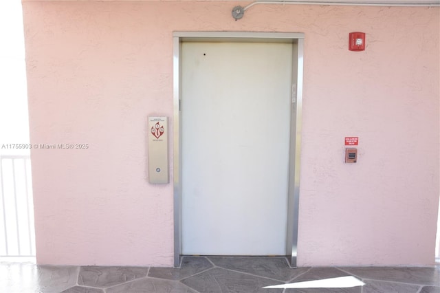 entrance to property with elevator and stucco siding