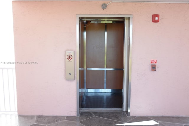 doorway to property featuring elevator and stucco siding