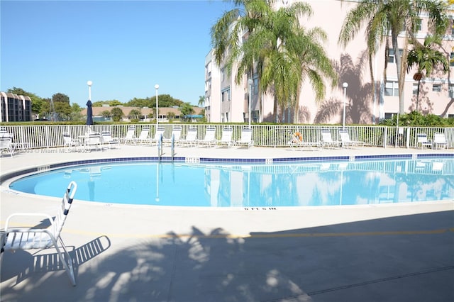 community pool with a patio area and fence