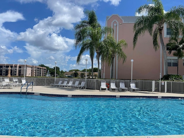 community pool with a patio and fence