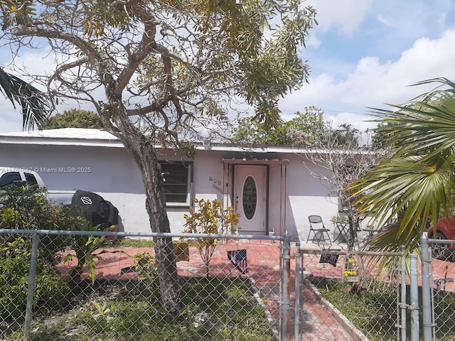 view of front of house featuring stucco siding, a fenced front yard, and a gate