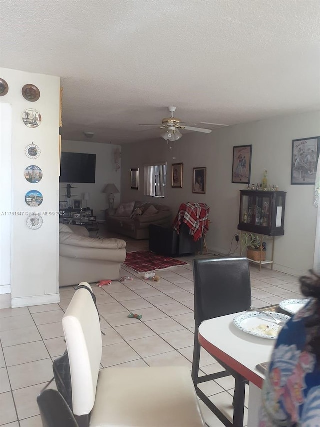 living area with light tile patterned floors, a textured ceiling, and a ceiling fan