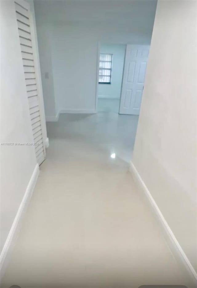 hallway with baseboards and finished concrete floors