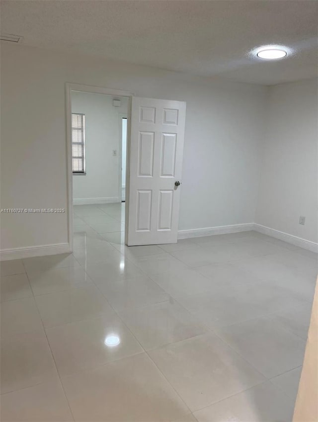 spare room with baseboards and a textured ceiling