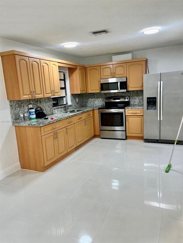 kitchen with visible vents, a sink, stainless steel appliances, stone counters, and decorative backsplash