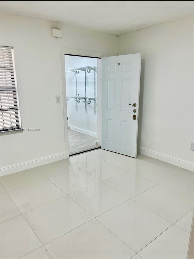 empty room featuring light tile patterned flooring and baseboards