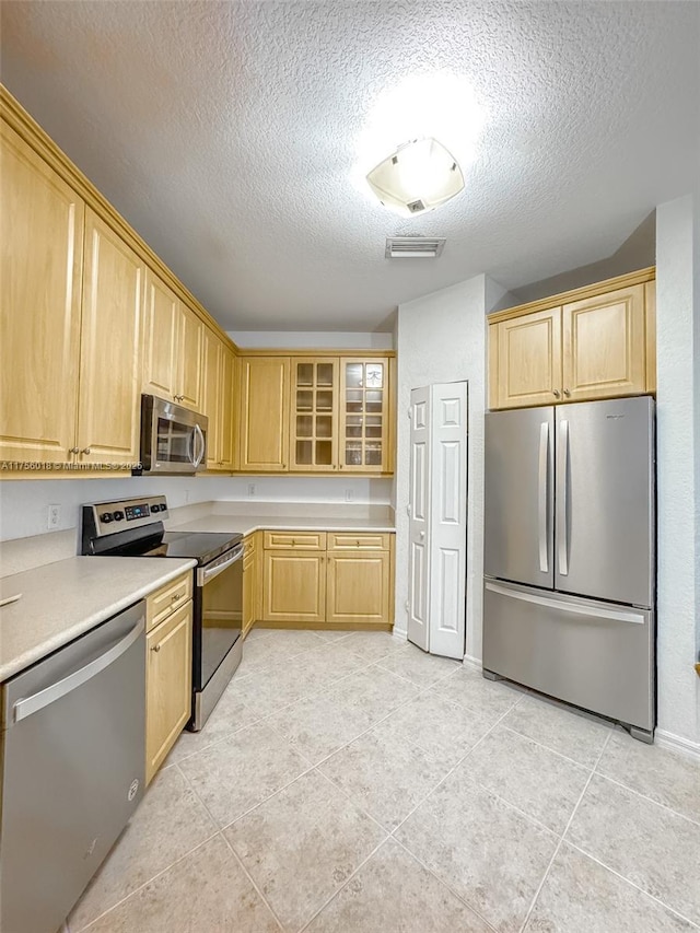 5737 NW 119th Dr Unit 5737, Coral Springs, FL 33076 - kitchen with light brown cabinetry, glass insert cabinets, stainless steel appliances, and light countertops