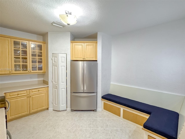 5737 NW 119th Dr Unit 5737, Coral Springs, FL 33076 - kitchen with light brown cabinets, a textured ceiling, freestanding refrigerator, light tile patterned floors, and glass insert cabinets