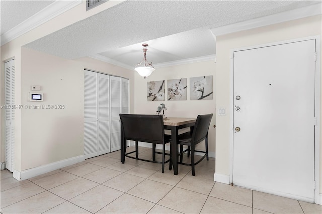 dining room featuring visible vents, ornamental molding, a textured ceiling, light tile patterned floors, and baseboards