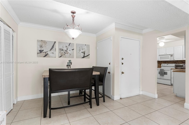 dining space with a textured ceiling, light tile patterned floors, baseboards, and ornamental molding