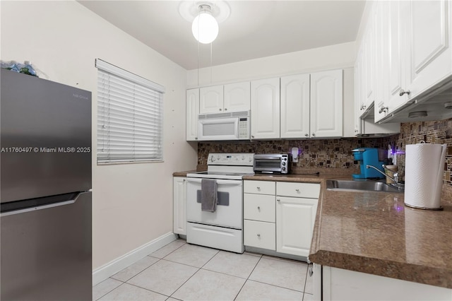 kitchen featuring a sink, white appliances, dark countertops, and white cabinets