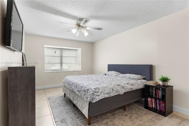 tiled bedroom featuring ceiling fan, baseboards, and a textured ceiling