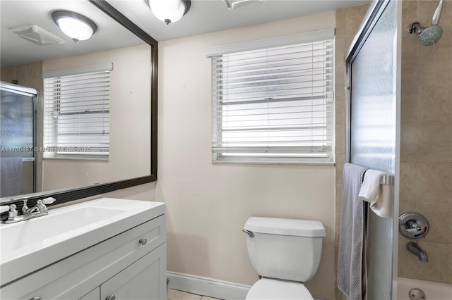 bathroom featuring combined bath / shower with glass door, baseboards, toilet, and vanity