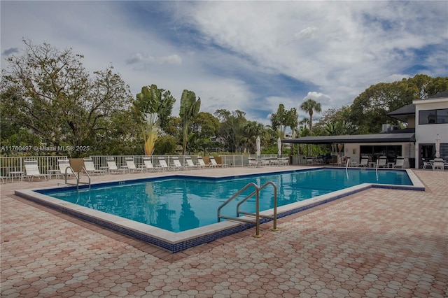 pool with a patio area and fence