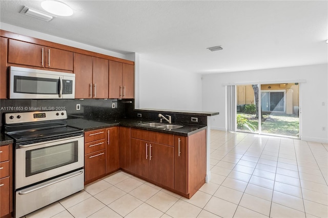 kitchen with visible vents, a sink, tasteful backsplash, appliances with stainless steel finishes, and a peninsula