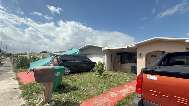 view of side of home featuring stucco siding, a garage, and fence