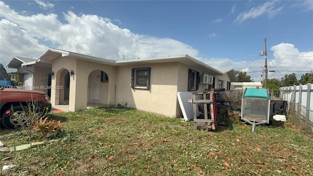 view of property exterior featuring fence, a lawn, and stucco siding